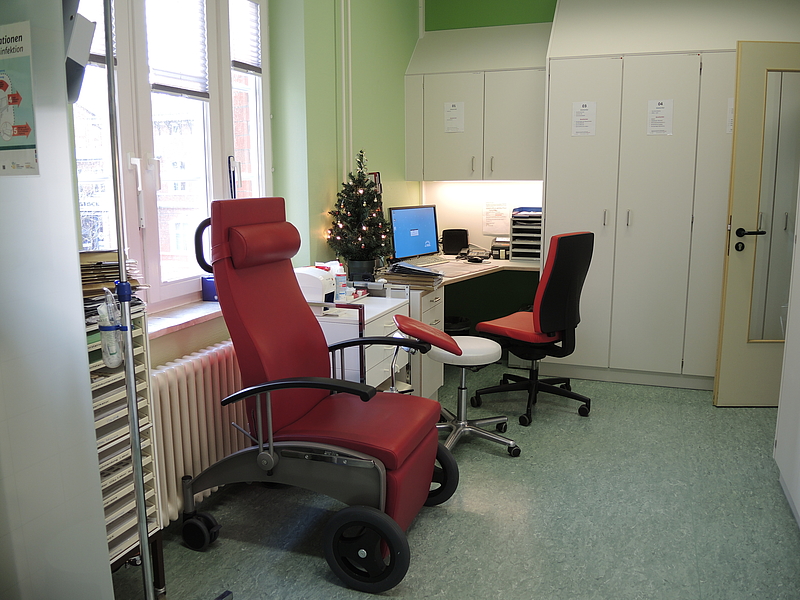Kleiner Raum mit Patientenrollstuhl und Computerarbeitsplatz